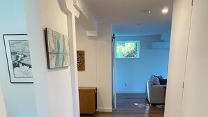 A hallway with wooden flooring, a patterned rug, and a bench.