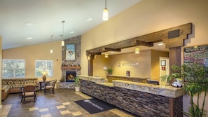 A reception area with a stone fireplace, a reception desk, and a seating area with a patterned sofa and chairs.