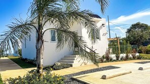 A white building with a small staircase and a palm tree in the foreground. - Beach Lote Villas - Villa 2 +Pool- Islote (Arecibo)