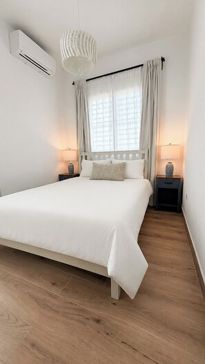 A bedroom with a large bed, two bedside tables with lamps, a ceiling fan, and a window with curtains. - Beach Lote Villas - Villa 2 +Pool- Islote (Arecibo)
