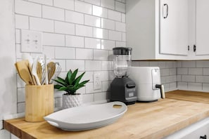 A kitchen with white subway tiles, a wooden countertop, a blender, a toaster, and a white cutting board. - 3 Queen Beds • Full Kitchen • Ideal for Long Stays (Abilene)