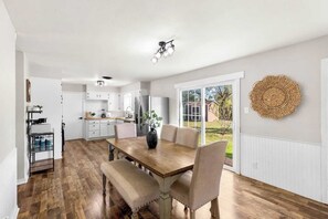 A modern kitchen with white cabinets, a stainless steel refrigerator, and a dining area with a wooden table and chairs. - 3 Queen Beds • Full Kitchen • Ideal for Long Stays (Abilene)