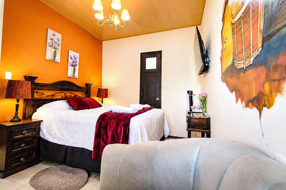 A hotel room with a bed, bedside tables, a lamp, a painting on the wall, and a door.