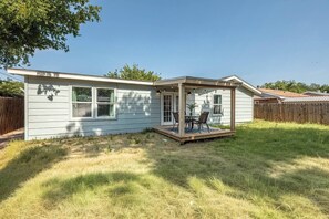 Einbungalow mit überdachter Terrasse, umzäuntem Garten und einer Holzterrasse.