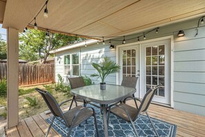 Eine überdachte Terrasse mit Tisch und Stühlen, einem Blumentopf und einer Lichterkette.