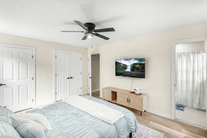 A bedroom with a bed, a ceiling fan, a TV mounted on the wall, and a door leading to another room. - Spacious 4BR with Long Kitchen and Relaxing Patio (Abilene)