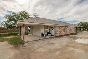 Une maison de plain-pied avec un porche couvert, un garage et une façade en briques.