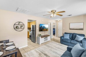 A modern living room with a sofa, a TV, and a ceiling fan.