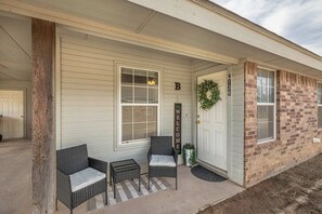 A house with a porch, a welcome sign, and a brick exterior.