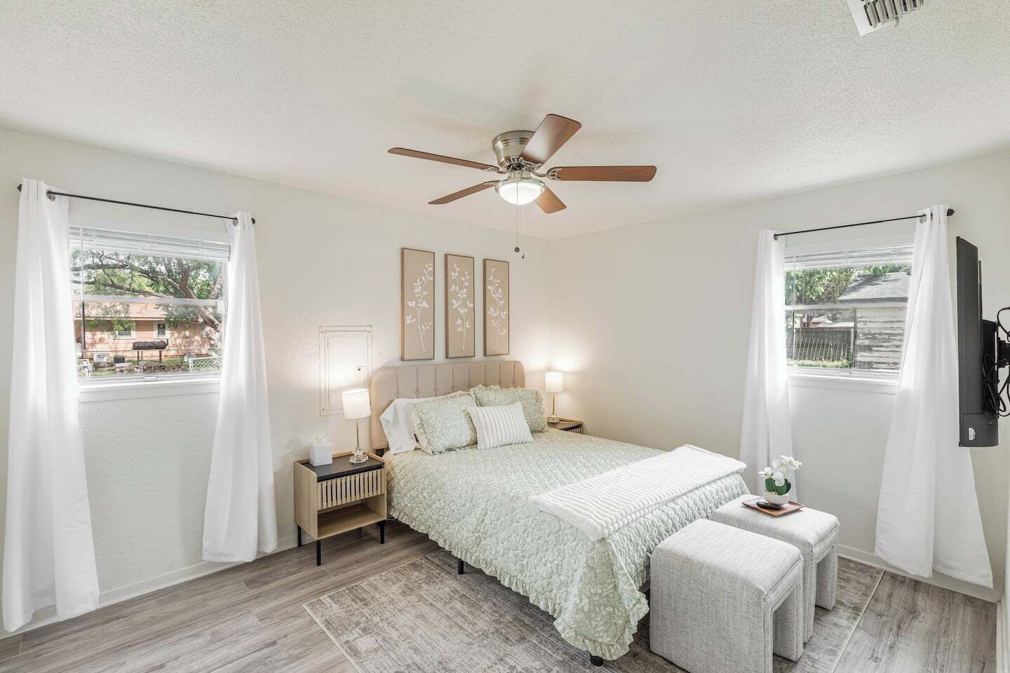 A bedroom with a bed, bedside tables, a ceiling fan, and a window with curtains.