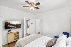 Ein Schlafzimmer mit einem Bett, einem Deckenventilator, einem Fernseher und einem Kleiderschrank.