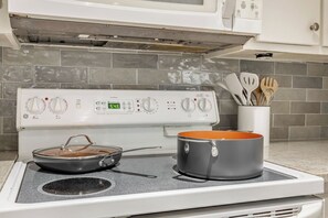 A kitchen with a white stove, a pot on the front burner, and a pan on the back burner. - 2BR + 2 baths: Fully Stocked! Ready for move in! (Abilene)