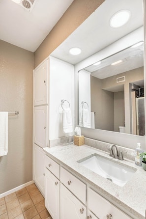 Une salle de bain avec un lavabo blanc, un miroir, un porte-serviettes et des toilettes.