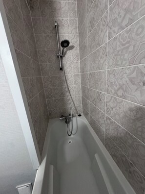 Une salle de bain équipée d’une baignoire, d’une douche et d’un drain.