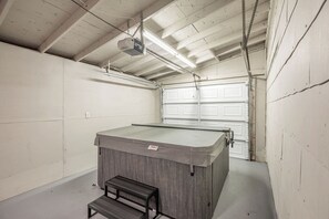 Een spa-ruimte met een bubbelbad, een houten bank en een projector aan het plafond.