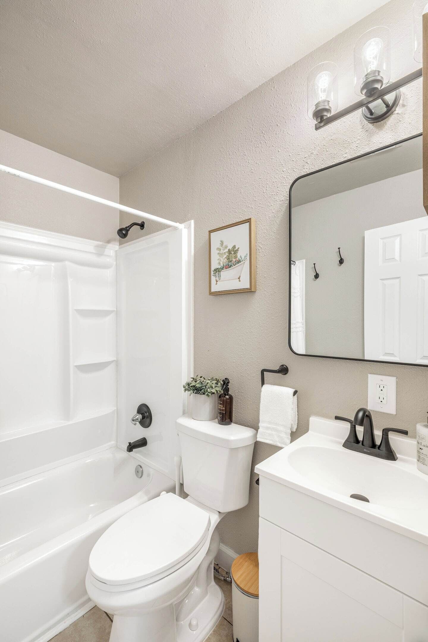 Un baño con bañera, inodoro, lavabo y espejo.
