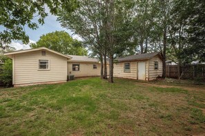 Un quartier résidentiel composé de trois maisons de plain-pied, chacune ayant un petit jardin devant et une clôture en bois.