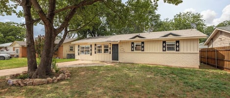 A single-story house with a front porch, a garage, and a fenced backyard.