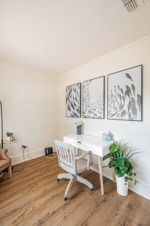 A room with a white desk, a white chair, and three framed wall art pieces depicting fish.
