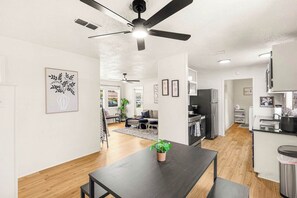 A modern kitchen with a black refrigerator, a stove, and a sink. There is a dining area with a black table and a potted plant. - Sunlit 4BR Modern Charmer with a Large Yard (Abilene)