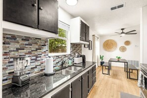 A modern kitchen with a black countertop, a blender, a toaster, and a sink.