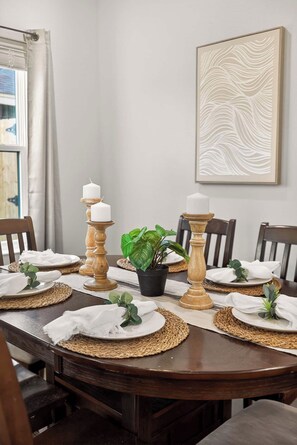Une table à manger dressée avec des sets de table, des bougies et une plante en pot.