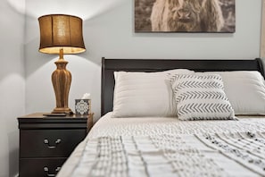 A neatly made bed with patterned pillows, a bedside lamp, and a framed picture on the wall.