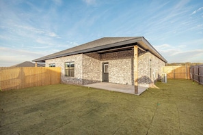 A single-story house with a brick exterior, a front porch, and a fenced backyard.