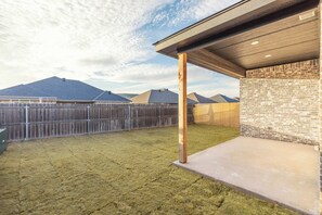 A fenced backyard with a patio area, a wooden fence, and a brick wall.