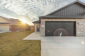 Un immeuble résidentiel à la façade en briques, avec une porte de garage sombre et un ciel dégagé.