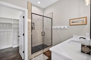Une salle de bain moderne avec une douche à parois de verre, un meuble-lavabo blanc et un tableau encadré au mur.