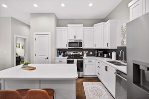 A modern kitchen with white cabinetry, stainless steel appliances, and a central island.