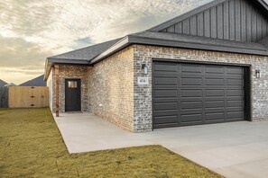 A residential building with a brick facade, a garage door, and a number '434' sign. - Brand New Home: Perfect for Long Stays (Buffalo Gap)