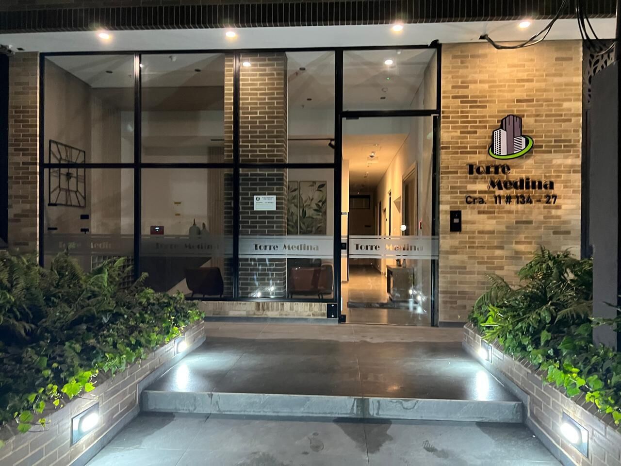 A hotel entrance with glass doors, a brick facade, and a sign reading 'Torres Medina.'