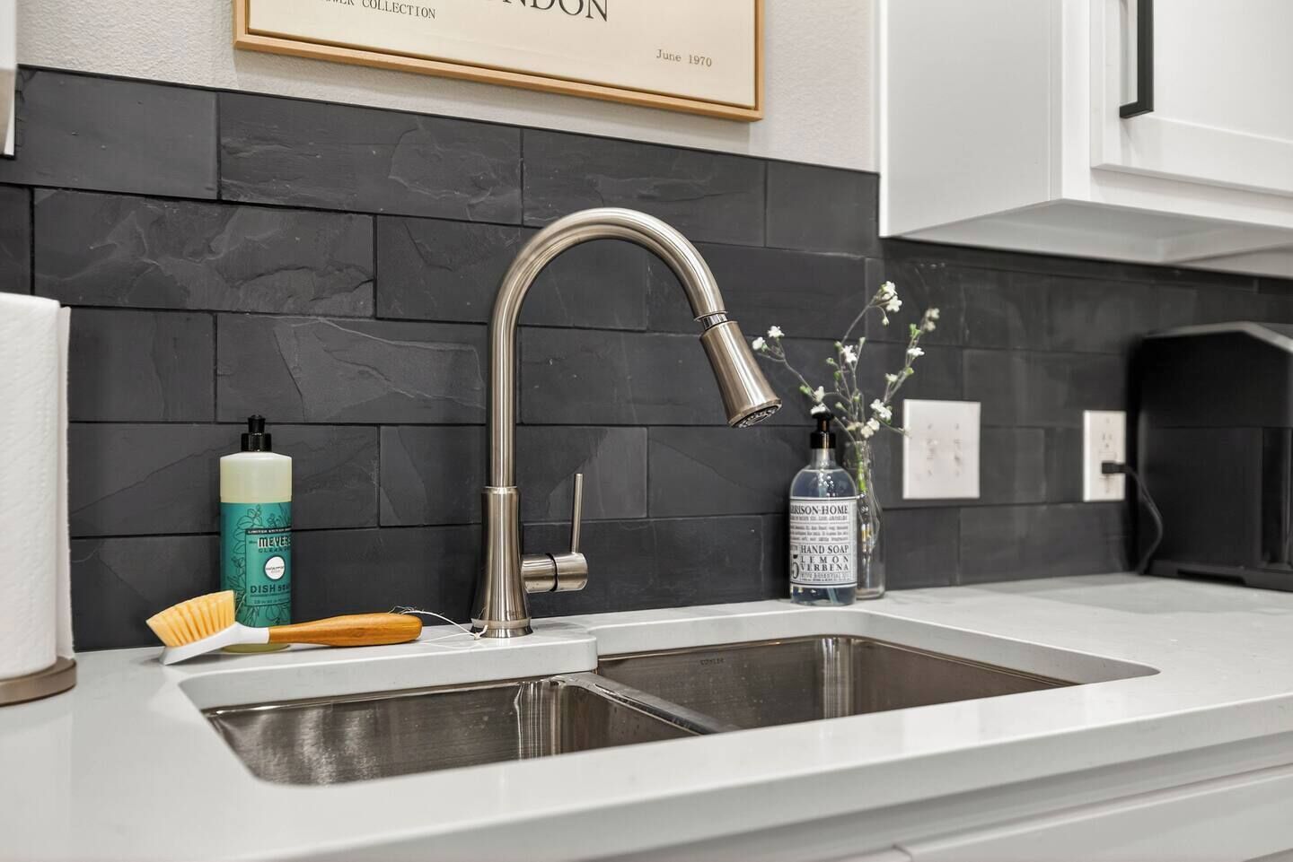A modern kitchen with a stainless steel sink, a faucet, and a soap dispenser.
