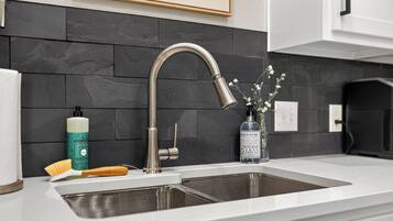 A modern kitchen with a stainless steel sink, a faucet, and a soap dispenser.