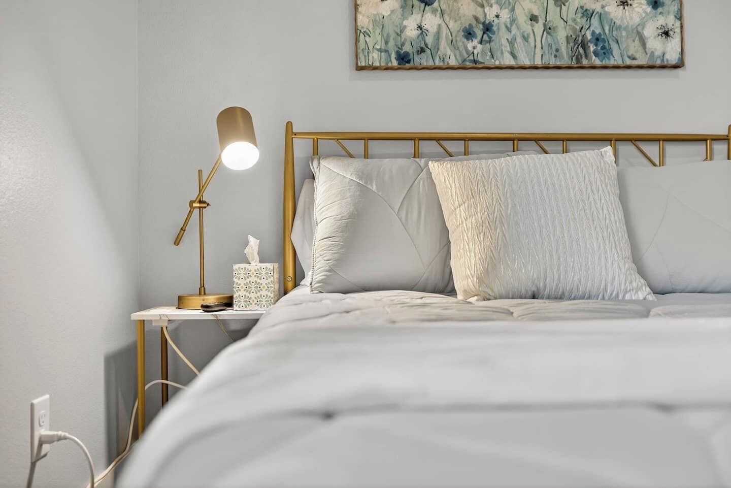A neatly made bed with a headboard, a bedside lamp, and a tissue box on a bedside table.