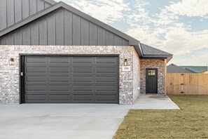 Un immeuble résidentiel doté d’un garage, d’une façade en briques et d’une clôture en bois.