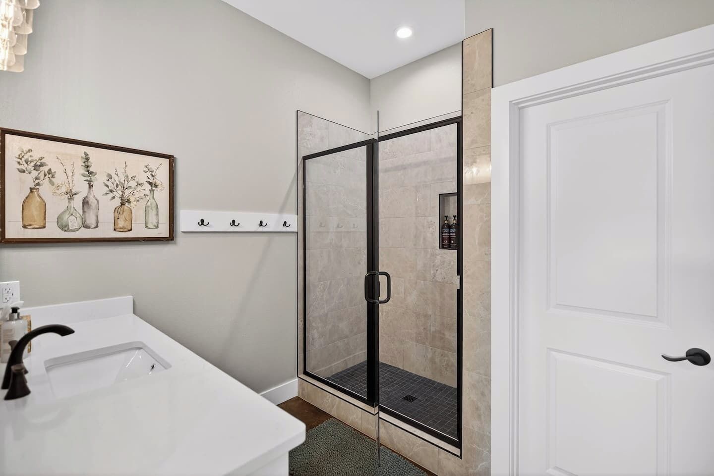 A bathroom with a white sink, a glass shower enclosure, and a door with a handle.