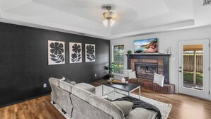 Un salon avec une cheminée, un canapé, une table basse et des œuvres d’art accrochées au mur.