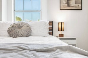 A neatly made bed with a decorative pillow, a bedside table with a lamp, and a framed picture on the wall. - Stylish 3BR+2 Bath Home w/Big Yard! (Abilene)