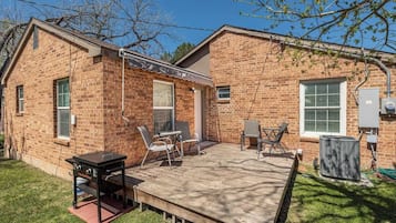 Una casa de ladrillo con un patio, mobiliario exterior y un equipo de aire acondicionado.