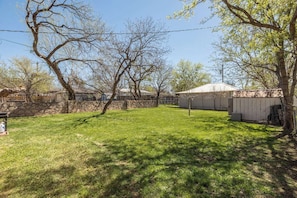 A backyard with a lawn, a shed, and a tree.