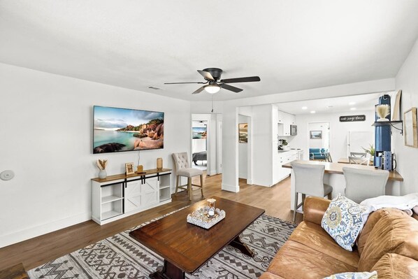 A modern living room with a wooden coffee table, a sofa, and a TV mounted on the wall.