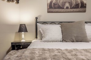A bed with a white and striped pillow, a white lamp on a bedside table, and a bear picture on the wall. - Modern Comfort 4BR House w/ Large Yard (Abilene)