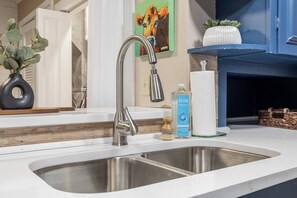 A kitchen with a stainless steel sink, a faucet, a bottle of ECOS dish soap, and a wooden brush. - Modern Comfort 4BR House w/ Large Yard (Abilene)