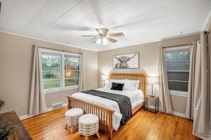 Une chambre à coucher avec un lit, des lampes de chevet, un ventilateur de plafond et une fenêtre avec des rideaux.