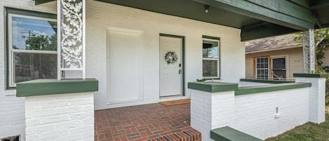 Ein Haus mit einer Ziegelfront, weißen Außenwänden und einem grünen Dach.