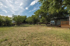 A backyard with a wooden deck, a fenced area, and a house in the background. - Peaceful 2BR Home with Modern Comforts (Abilene)