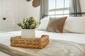 A bed with a woven basket and a white vase with green plants. - Peaceful 2BR Home with Modern Comforts (Abilene)
